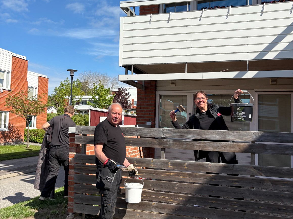 Personal som oljar in uteplatser på Lommarvägen, glada och vinkandes till kameran.